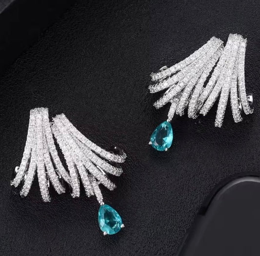 Aretes de joyería de lujo pedreria blanca, tonos plateados y detalle de piedra color Aqua.