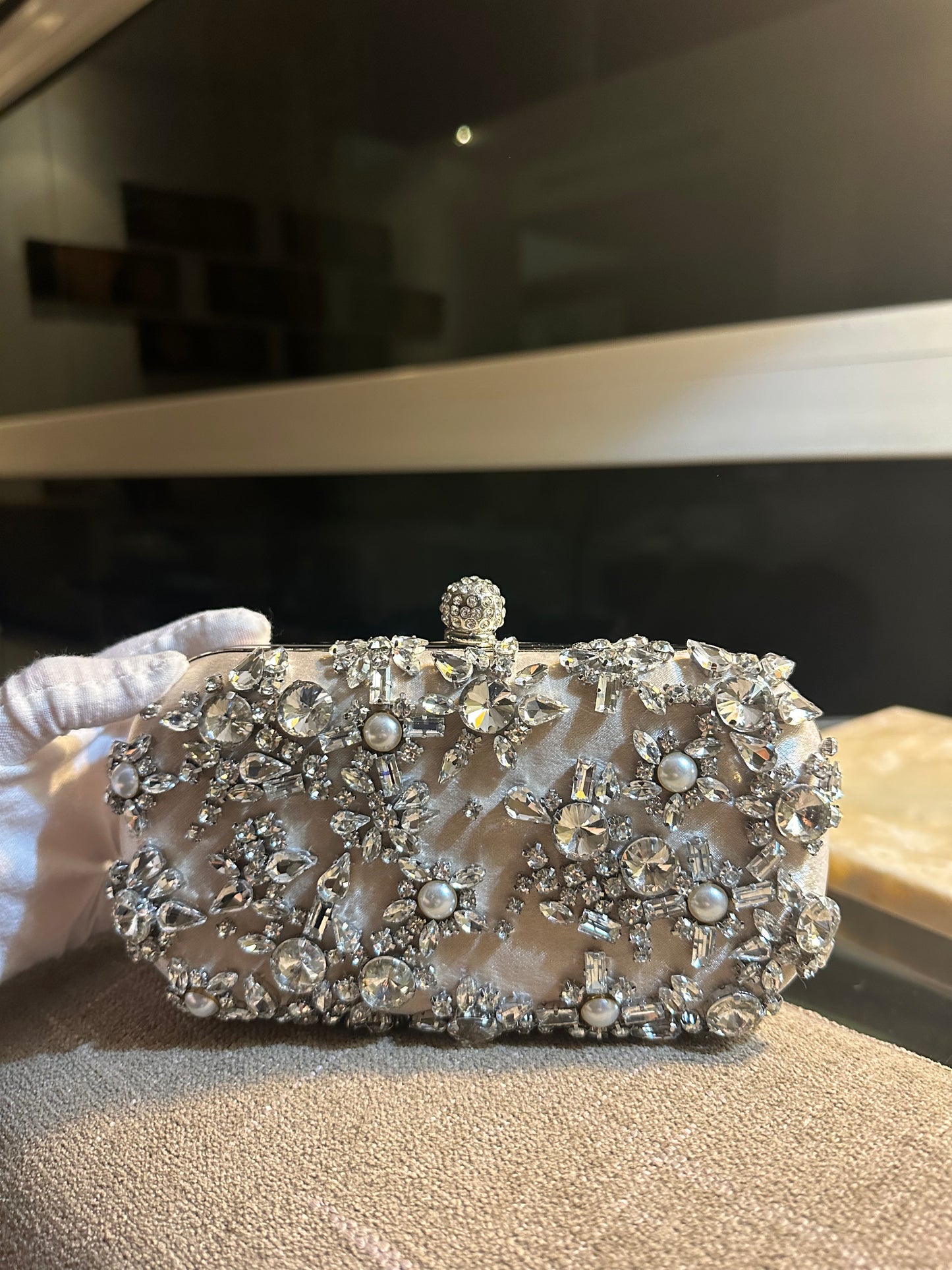 Clutch con perlas, piedras de distintos tamaños en tono nude y gris.