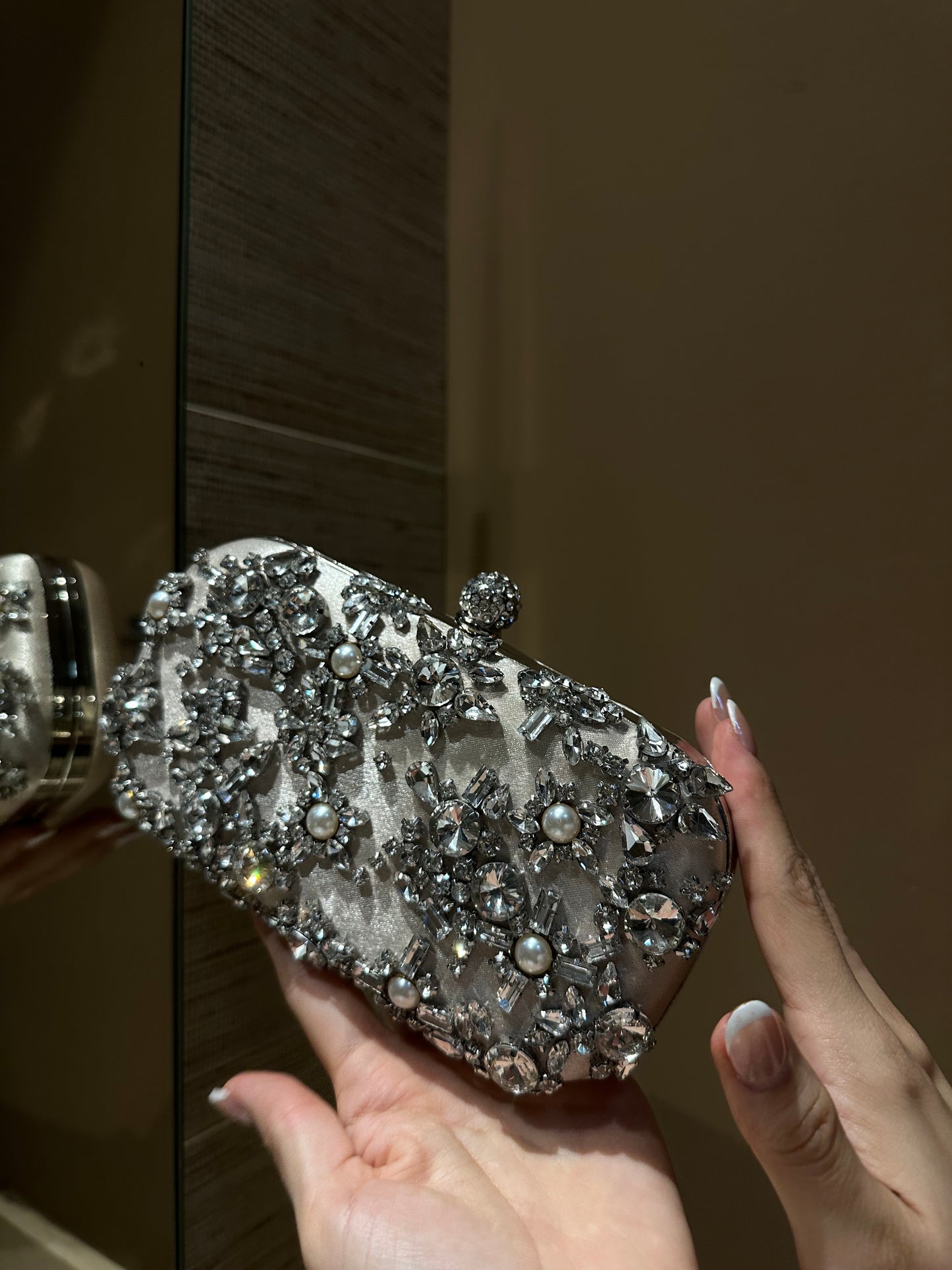 Clutch con perlas, piedras de distintos tamaños en tono nude y gris.