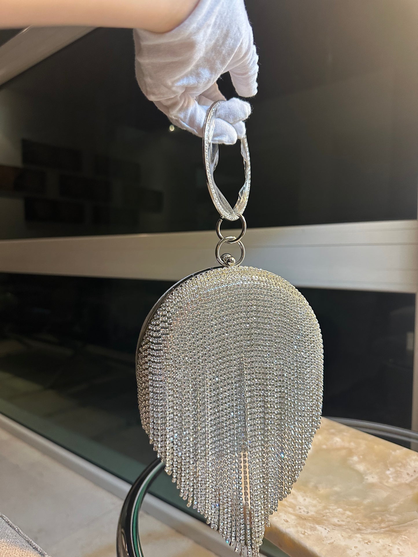 Bolso de mano con borla de diamante para mujer con tiras colgantes de pedrería base plateada.